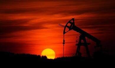 drilling rig silhouetted against setting sun