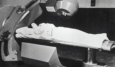 female patient lying down receiving Cobalt 60 cancer therapy. 1951