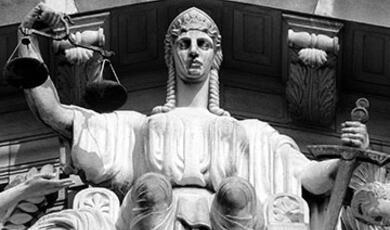 female statue sitting holding scales and sword of justice