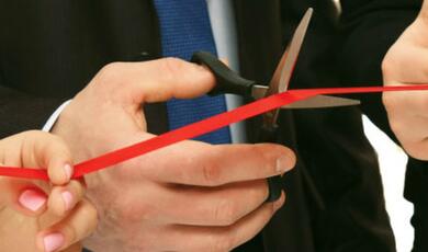 man in suit cutting red ribbon