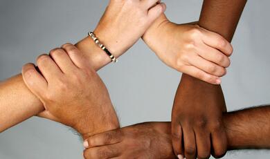 four hands clasping each other to form a circle
