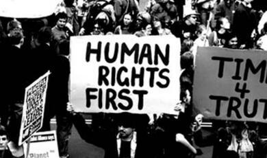 Protester carrying sign reading 'human rights first'