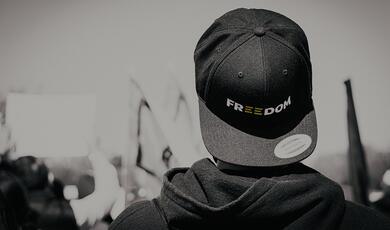 back of protester with cap saying 'Freedom' on