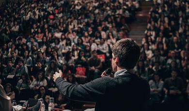 close up of speaker from behind addressing large audience