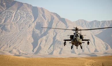 Army helicopter flying over desert landscape