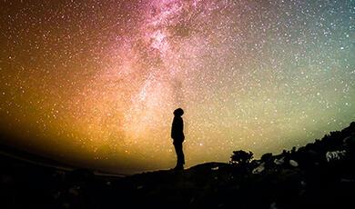 Sillhouette of man staring up at the stars