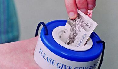 hand putting a £50 note into a charity box