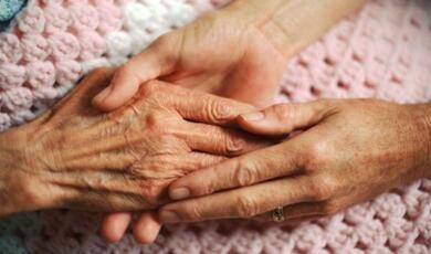 a pair of hands cradling an elderly hand