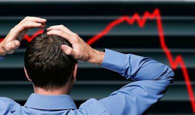 man with hands on the top of his head looking at a chart of stock falling