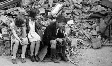Children sitting on a pile of rubble in London 1940s
