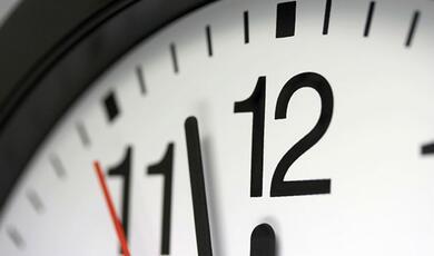 close up of clock face pointing at two minutes to twelve