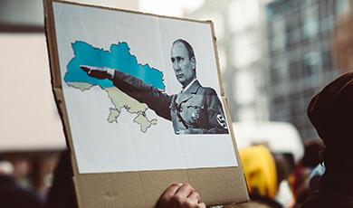Putin dressed as a Nazi with an image of Ukraine on a piece of cardboard