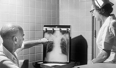 a black and white photograph of a nurse and doctor examining an x-ray
