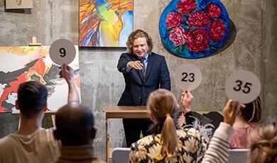 an auction scene with people holding up the numbers 9, 23 and 35