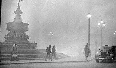 a black and white photograph of people in the London smog