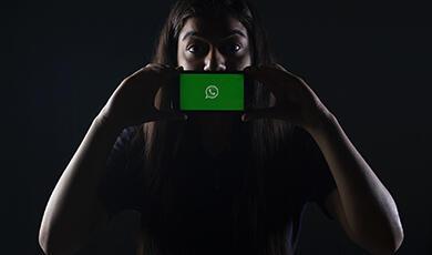 Woman in near darkness holding mobile phone up to the camera