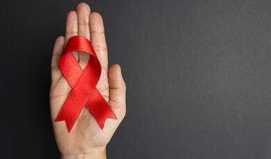 Hand holding red AIDS awareness ribbon