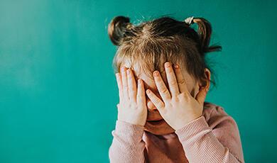 Young child covering her eyes with her hands