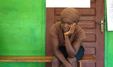 Young black woman in headscarf waiting on bench