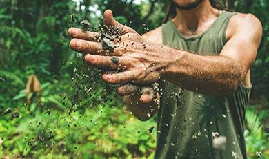 a man clapping his hands together that are full of soil