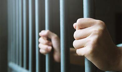 a pair of hands gripping prison cell bars