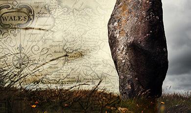 an old map of Wales next to an ancient stone