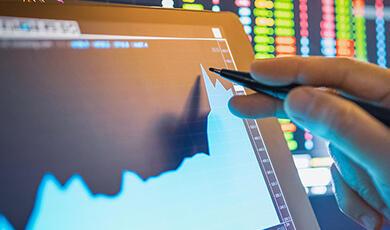 Hand holding pen up to tablet showing digital graph