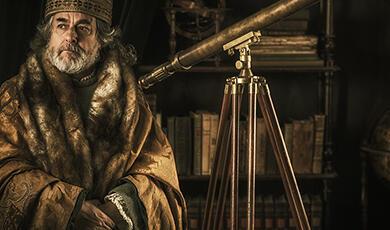 Medieval astronomer in fur-lined robe with telescope