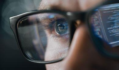 Computer screen reflected in man's glasses