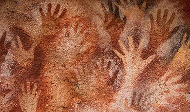 Many red and orange  hands spray painted onto brown wall