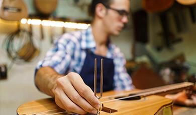 Man using tuning fork on guitar