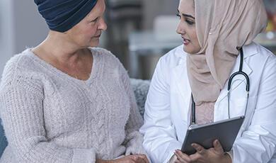 a woman talking to a doctor who is holding a tablet