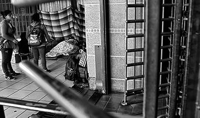 a black and white photograph of someone sleeping on the streets