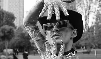 Man in fedora, sunglasses and sequined goves poses for the camera