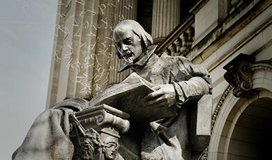 Statue of Shakespeare with open book, with maths symbols rising out of it