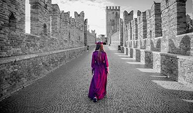 Medieval woman in red walking down castle battlement