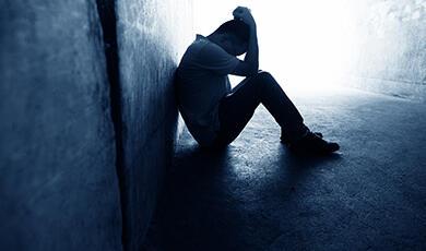 Shadowy figure sitting, head in hands, in tunnel