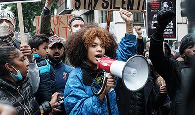 a woman speaks through a megaphone at a protest
