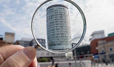 a magnifying glass with the Rotunda in Birmingham, UK