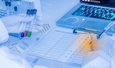 three vials of liquid next to a laptop and a clipboard