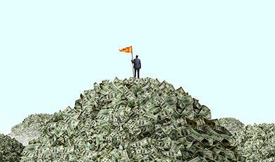 Toy man with flag standing on top of a large pile of paper money