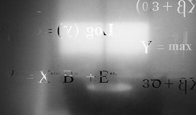 Mathematical equations and symbols visible on a frosted glass surface