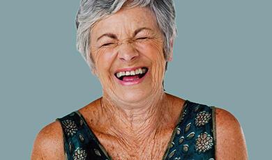 Close-up of a senior woman with short grey hair laughing joyfully