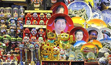 A souvenir stall at a Beijing night market selling various items, including plates featuring images of Chinese leaders like Xi Jinping and Mao Zedong