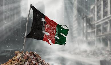 Tattered Afghani flag flying over rubble