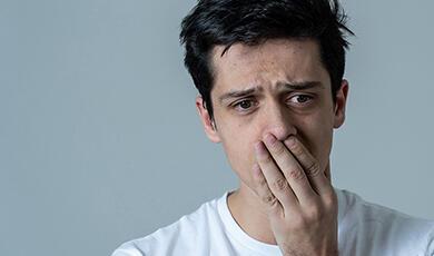 A man with a worried expression covers his mouth with his hand
