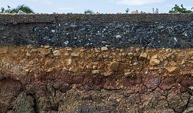 Cross-section of ground showing layers of asphalt, gravel, and soil