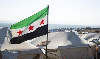 Syrian flag flying over camp tents