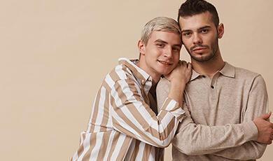 Minimal waist-up portrait of a happy gay couple looking at the camera