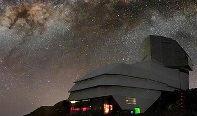 The Vera C. Rubin Observatory illuminated at night under a sky filled with the Milky Way galaxy